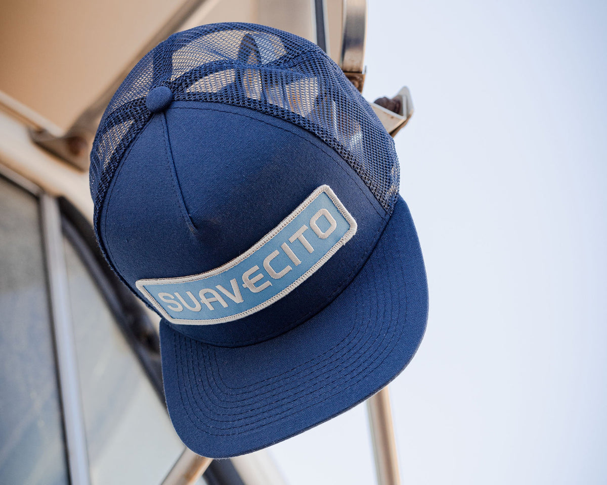 blue suavecito hat with white embroidered text and light blue background "suavecito"